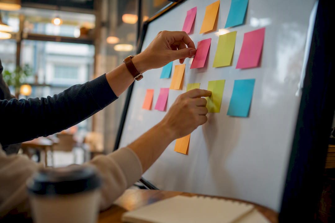 Hands moving sticky notes on whiteboard